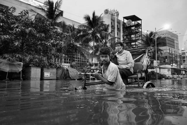 சூரத் நகரில் ஒரு ரிக்ஷா தொழிலாளி தனது வாடிக்கையாளரை கரை சேர்க்க முயல்கிறார்